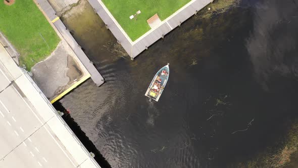 A top down shot over a boat in a canal on a cloudy day. The camera is looking down and pan right as alt