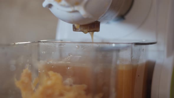 4K Closeup view auger juicer pressing homemade orange juice and pulp. Fresh healthy drink Vegan food