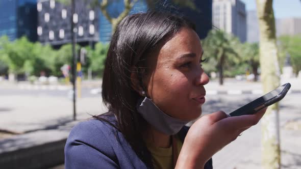 African american woman wearing face mask talking on smartphone in street alt