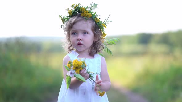 Portrait of a Little Girl in a Wildflowers Wreath on Her Head