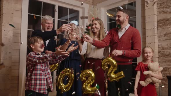Happy Family Celebrates New Year 2022 Laugh and Hug Clanging Glasses