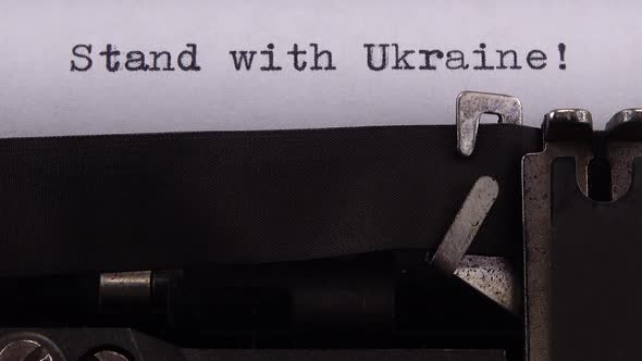 Typing phrase "Stand with Ukraine !" on retro typewriter. alt