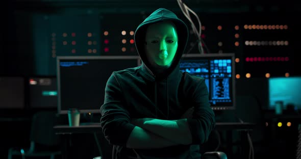 Dangerous Internationally Wanted Hacker with Covered Face Looking Into the Camera In the Background alt