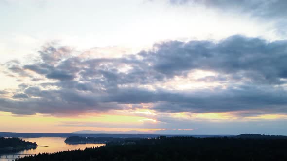 Dark ominous clouds spread across a deep golden amber sunset sky, aerial hyperlapse alt