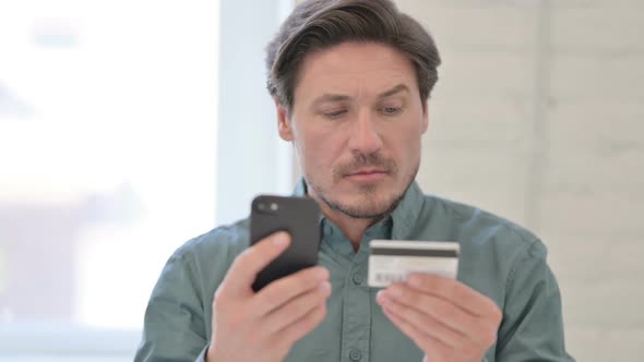 Portrait of Middle Aged Man with Successful Online Shopping on Smartphone alt