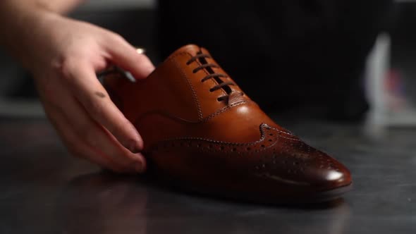 Closeup Hands of Male Shoemaker Puts Old Light Brown Leather Shoe Near Repaired Shiny alt