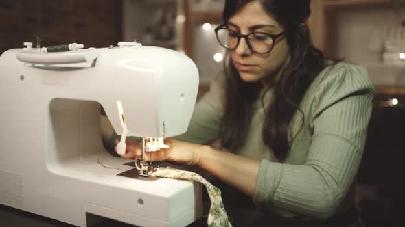 Crop seamstress pulling out thread of sewing machine in atelier alt