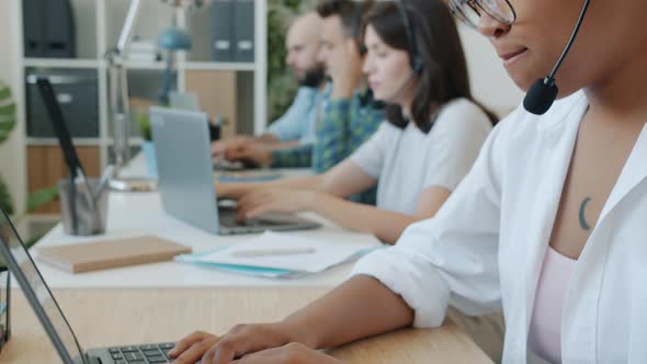 African American Lady Concentrated on Conversation Working in Call Center with Colleagues alt