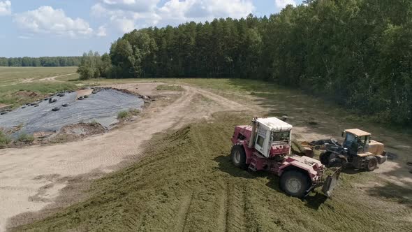 Aerial view of tractors tamp the silage in the Silo Trench next to the forest 04 alt
