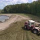 Aerial view of tractors tamp the silage in the Silo Trench next to the forest 04 - VideoHive Item for Sale
