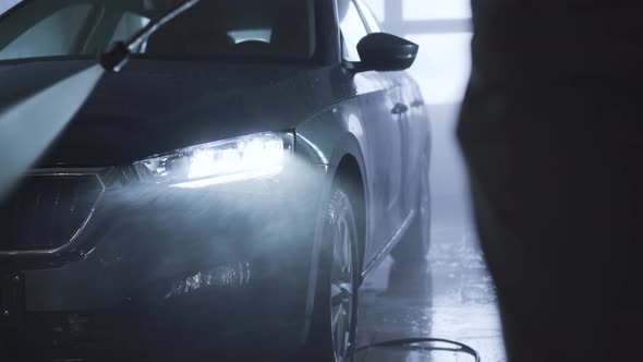 Close-up of Car Wash in Auto Care Shop. Unrecognizable Employee Cleaning Vehicle Manually with High alt