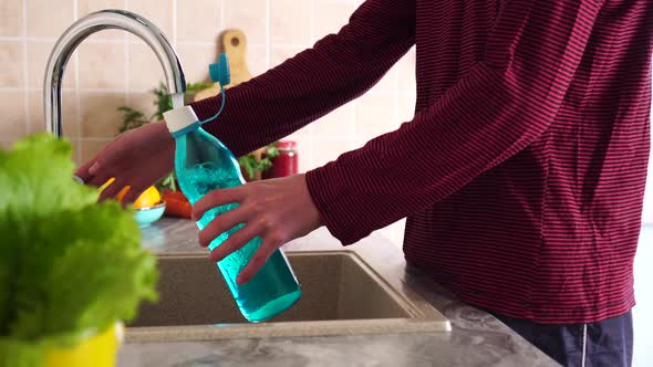 Reusable glass water bottle. Man pours water from the tap. Zero Waste Lifestyle alt