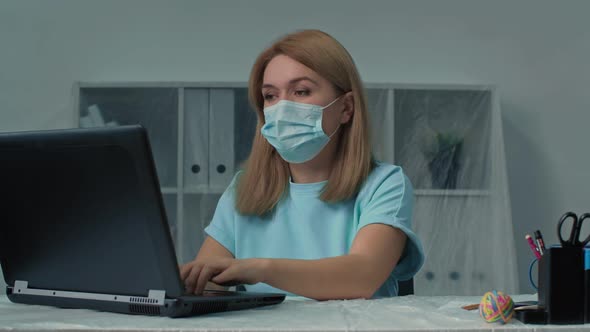 Middle Aged Businesswoman in Medical Mask Sitting Working Typing Email on Laptop Using New Computer alt
