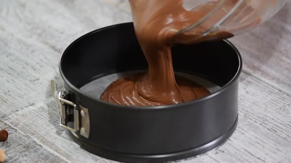 Pouring chocolate batter into pan. Woman in the kitchen making chocolate cake.	 alt