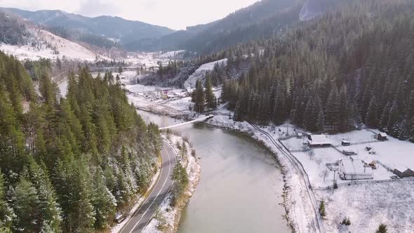 Mountain River Flowing Between A Forrest And A Road In The Winter