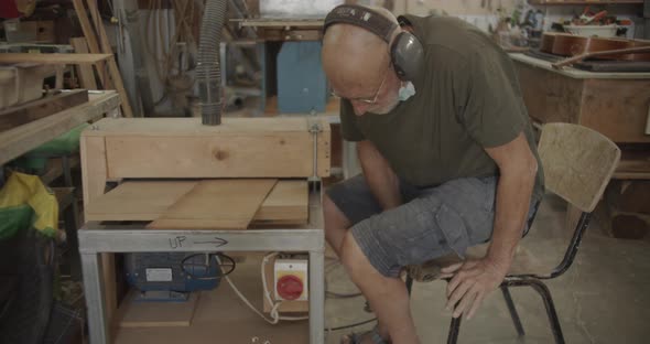 Old carpenter sitting by a machine