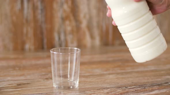Female Hand Pouring Milk From Bottle To Glass alt