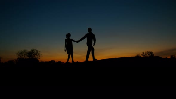 Silhouette of Guy and Girl Walking on the Hills. alt