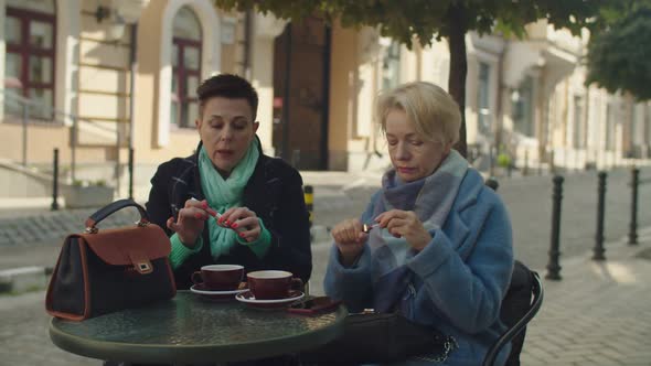 Middleaged Women Smartening Up Putting on Lipstick Outdoors alt