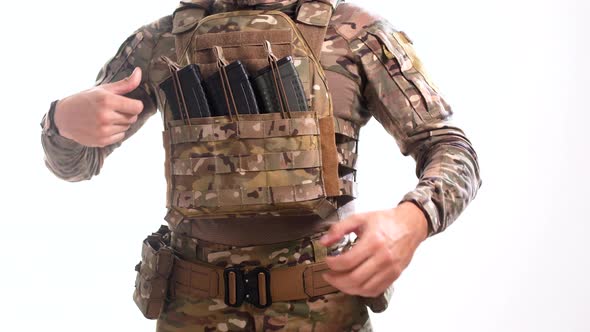 Man in combat camouflage and body armor fixes loaded rifle magazines in their pouches