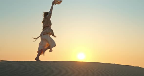 Happy Excited Woman Running By Sand Dune with Golden Sunset on Background alt