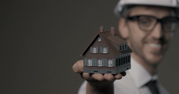 Smiling architect holding a model house