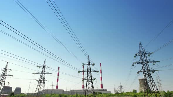 A Power Energy Lines of Highvoltage Transmission Pylons with Heat and Power Plant and Clear Blue Sky