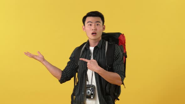 young Asian tourist man with backpack doing opening hand and invite gestures