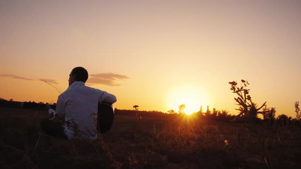 Alone Man Playing Guitar Outdoors at Sunset Time alt