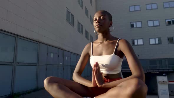 Slow motion shot of young woman meditating while sitting outdoors alt
