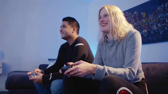 Couple is sitting on a couch while gaming together and having fun alt