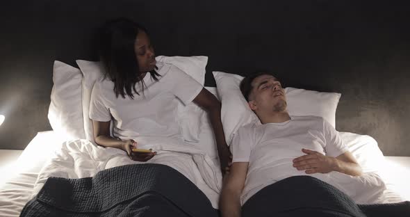 Multi-ethnic Couple Lying in Bed Together. Wife Not Able To Sleep with Her Husband Because He