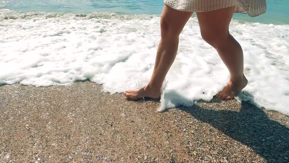 Seashore with Waves and a Woman Walking Along It alt