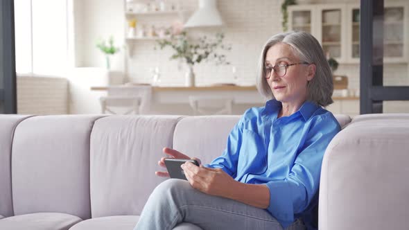 Old Senior Woman Holding Cell Phone Video Conference Calling at Home alt