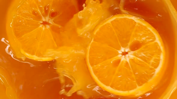 Orange falling and splashing into range juice in super slow motion and dividing into halves.