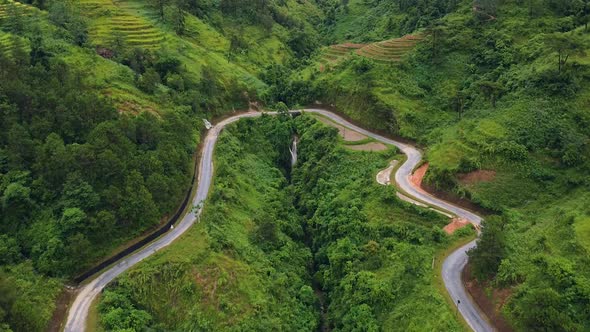 A Winding Road in the Mountains with Lush Greenery, Waterfall and Rice Terraces. alt
