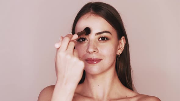 Nude Makeup Woman Applying Face Powder with Brush alt