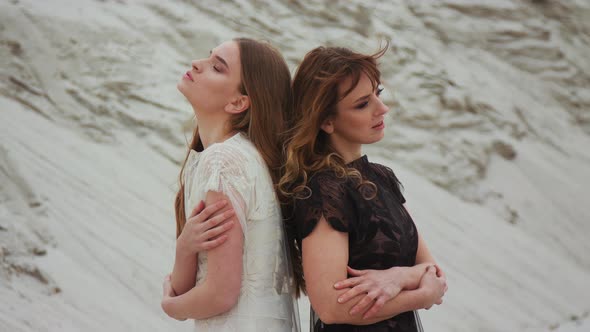 Portrait of Caucasian Beautiful Young Females in White and Black Dresses Back To Back and Smiling  alt