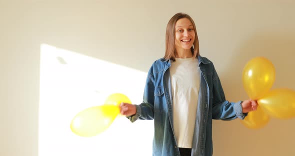 young beautiful woman having fun with golden balloons at home party. Throws up balloons. happy girl 