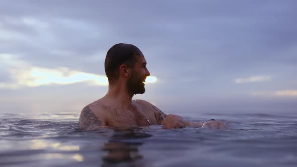 Male Model Swimming in Water With Backdrop of Defocused Majestic Dusk Heavens alt