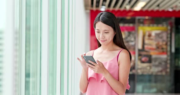 Asian Woman use of cellphone inside shopping center alt