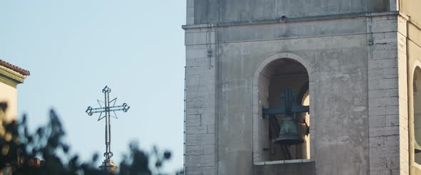 An old clock tower with bell and cross alt