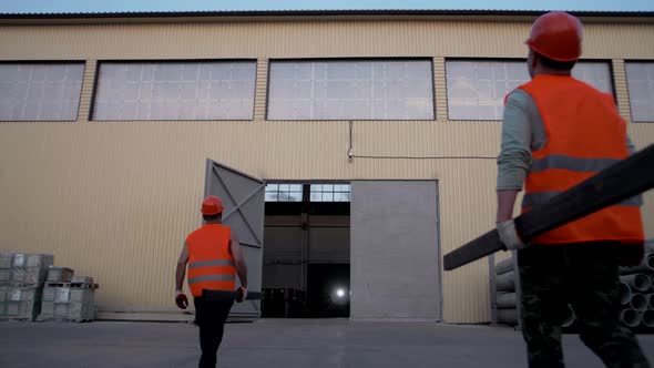 The beginning of the working day at the metal base. Workers carry metal structures to the warehouse alt