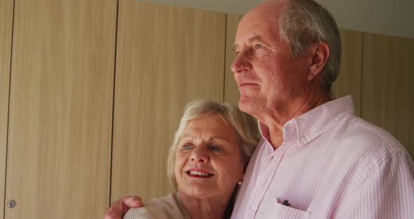 Senior couple in social distancing hugging each other in retirement house alt