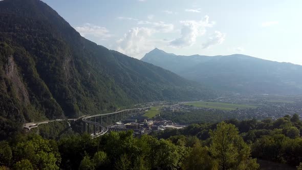 Aerial approach to an industrial area and huge bridge in the mountains. Polluted valley in the frenc alt