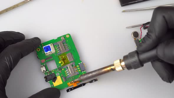 the Master Soldering Iron Solders the Mobile Phone Board with a Soldering Iron alt