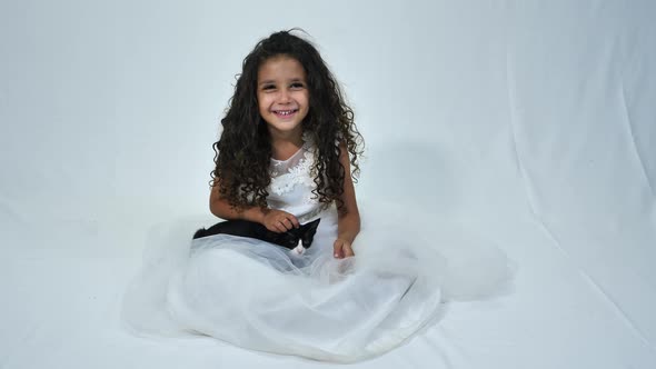 Portrait of cheerful little girl stroking her pet kitten on white background alt