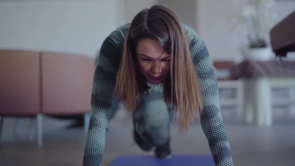 Front View of Happy Confident Young Woman Training on Exercise Mat at Home or in Gym. Portrait of alt