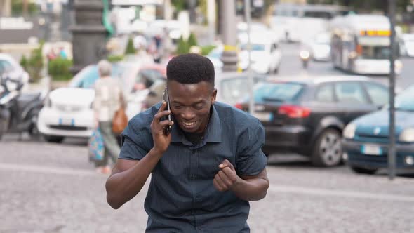 good news, win, success - Young African man on the phone rejoicing in the street alt