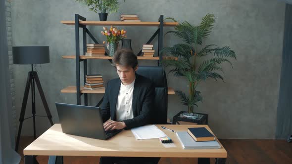 Young Perspective Businessman is Actively Working While Sitting at the Table in the Office